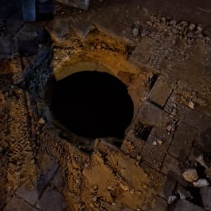 בור פתוח בכביש עם אבנים ועפר סביבו