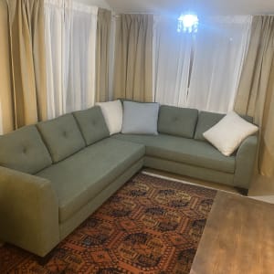 ספה ירוקה עם כריות לבנות על שטיח צבעוני