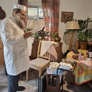 אדם בלבוש מסורתי ליד שולחן עם חפצים שונים