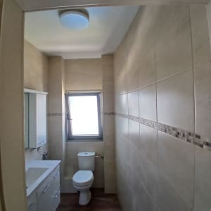 חדר אמבטיה עם אריחים בהירים ושירותים