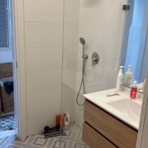 מקלחת עם ראש מקלחת, כיור ומוצרי טיפוח על השיש