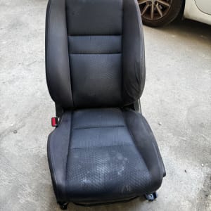מושב רכב שחור על רצפת בטון ליד רכב