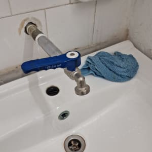 ברז עם ידית כחולה על כיור לבן