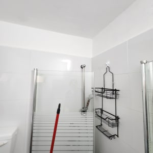 מקלחת עם דלת זכוכית, מגב אדום, מדף מתכת שחור