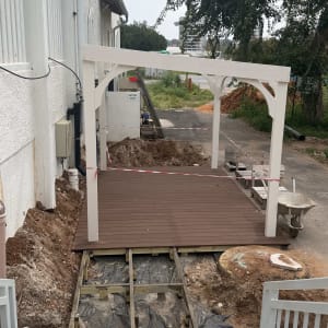 פרגולה לבנה עם רצפת עץ בבנייה ליד בניין