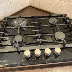 כיריים גז שחורות עם ארבעה מבערים וכפתורי שליטה