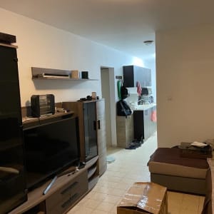 חדר עם טלוויזיה, ארגז קרטון ומטבח קטן