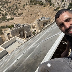 אדם יושב על גג עם נוף של בניינים והרים