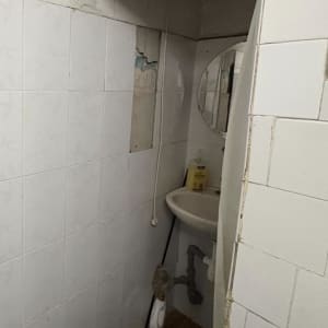 חדר אמבטיה עם קירות מתקלפים וכיור קטן