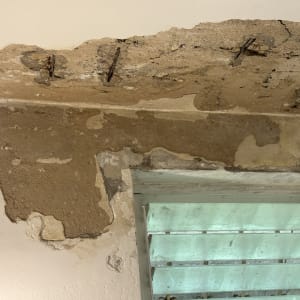 נזקי בטון וטיח בתקרה ובקיר עם ברזלי זיון חלודים