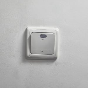 מתג חשמלי על קיר לבן עם כיתוב 