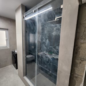 מקלחון זכוכית בחדר אמבטיה מודרני עם קירות אפורים