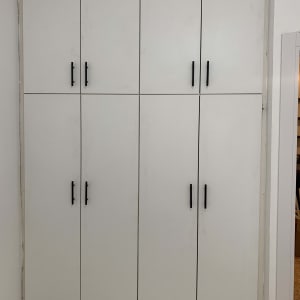 ארון לבן עם ידיות שחורות מותקן בקיר