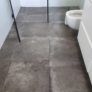 רצפת חדר אמבטיה עם אריחים אפורים ומקלחון זכוכית