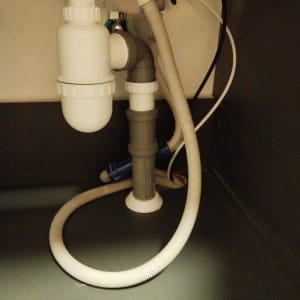 צנרת מתחת לכיור עם מחברים וצינורות פלסטיק
