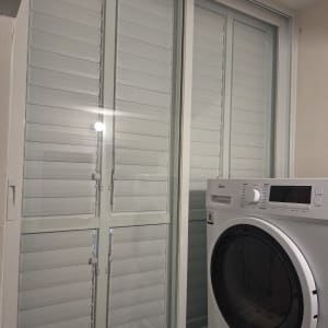 חלון אלומיניום עם תריסים ליד מכונת כביסה