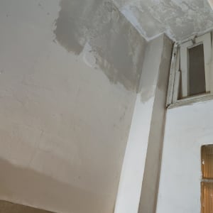 קיר עם תיקוני צבע וטיח ליד חלון קטן