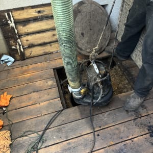 צינור ירוק מחובר למשאבה בבור פתוח על רצפת עץ