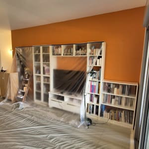 קיר צבוע בכתום עם רהיטים מכוסים בניילון