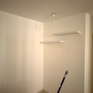 קיר צבוע עם מדפים ומנורה