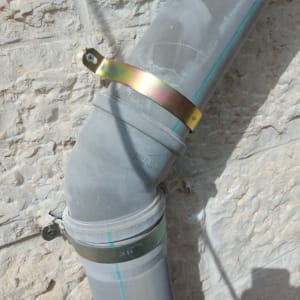 התקנת צינור ניקוז ואינסטלציה חיצוני על קיר אבן בעזרת חבקים