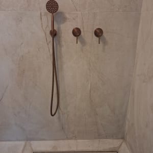 מקלחת עם ראש טוש וברזים על קיר שיש