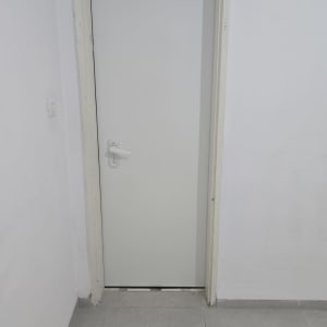 דלת לבנה עם ידית כסופה על קיר לבן