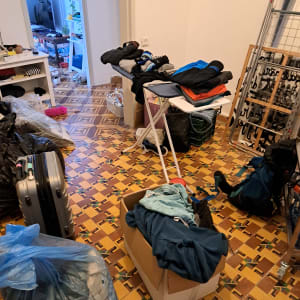 חדר עם בגדים על קרש גיהוץ, קופסאות ותיקים