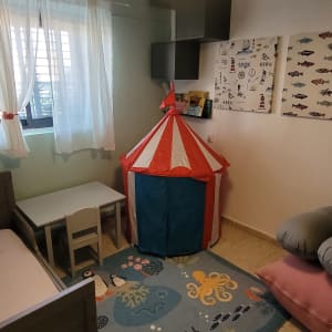 חדר ילדים עם שטיח צבעוני ואוהל משחקים