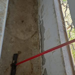 מגב אדום על רצפה מלוכלכת ליד קיר מתקלף