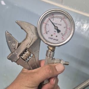 מד לחץ מים ומפתח ברגים ביד אדם