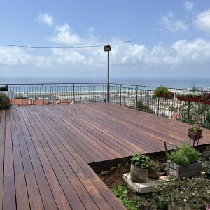 דק עץ עם עציצים ופרחים מסביב