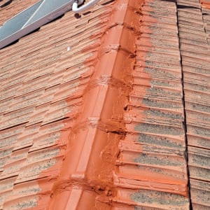 גג רעפים עם צינור לבן ומריחת חומר אטימה כתום