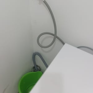 ברז עם צינור וגיגית ירוקה על הרצפה