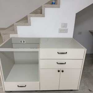 ארון מטבח לבן עם מגירות ודלתות ליד גרם מדרגות