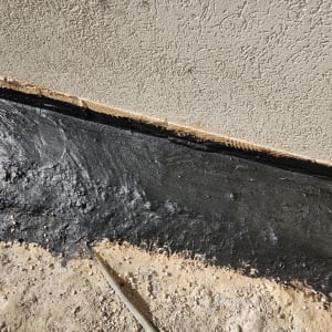 איטום קיר עם חומר שחור על הקרקע