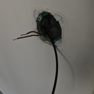 חוטי חשמל יוצאים מקיר עם חור