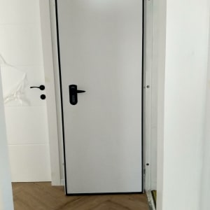 דלת לבנה עם ידית שחורה במסגרת שחורה