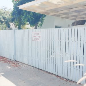 שער חשמלי לבן עם שלט אזהרה