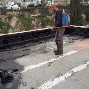 אדם מבצע איטום על גג עם ציוד מתאים