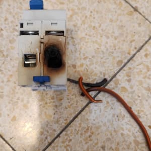 מפסק חשמלי שרוף עם חוטים חשופים על רצפה