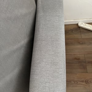 ספה אפורה עם משענת יד על רצפת עץ