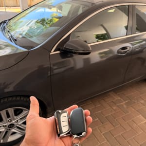 מפתח רכב ביד מול מכונית חונה