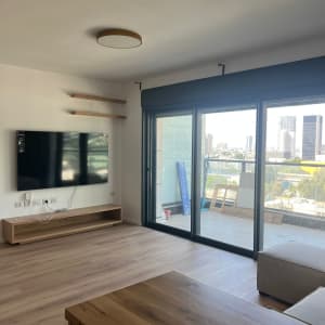 חדר עם רצפת עץ, מדפים וטלוויזיה על הקיר.