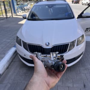 יד מחזיקה חלק רכב מול מונית לבנה