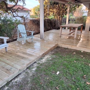 דק עץ עם כיסאות ושולחן בגינה