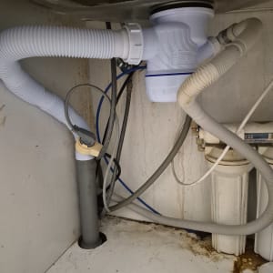 צנרת מתחת לכיור עם חיבורים וצינורות פלסטיק