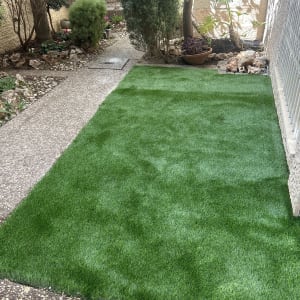 דשא סינתטי בגינה עם שביל ואדניות צמחים