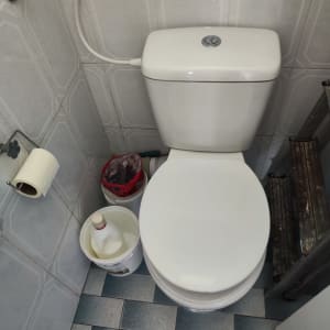 אסלת מונובלוק לבנה עם ניאגרה גלויה וצינורית בידה בחדר שירותים
