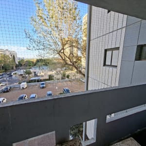 רשת הגנה על מרפסת עם נוף עירוני ועצים